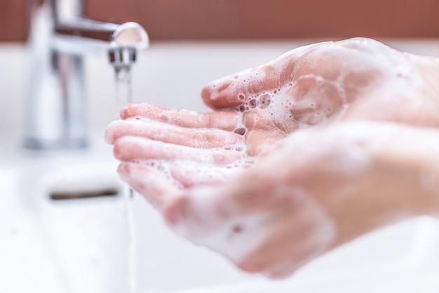 욕실에서 물과 액체 비누로 손을 씻습니다. 위생 안티 바이러스 개념입니다.