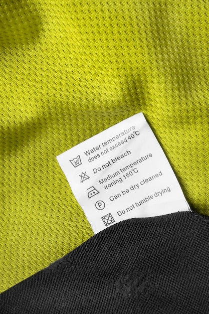 washing instructions clothes label on green and black fabric background