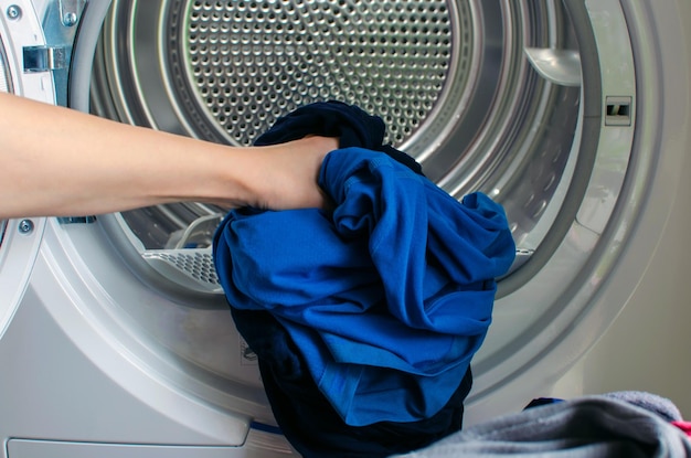 Washing machine for clothes woman hand loads tumble dryer and tumble dryer