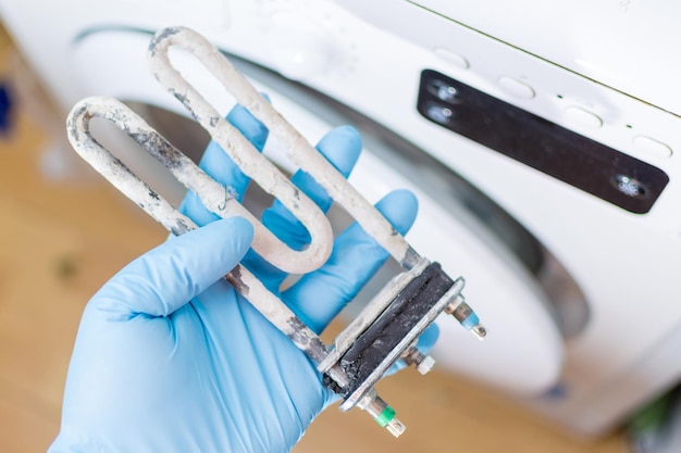 Washing machine repair Hand of repairer with turbular electric heating element