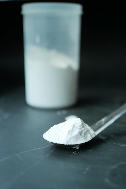 Washing powder in plastic spoon on black background