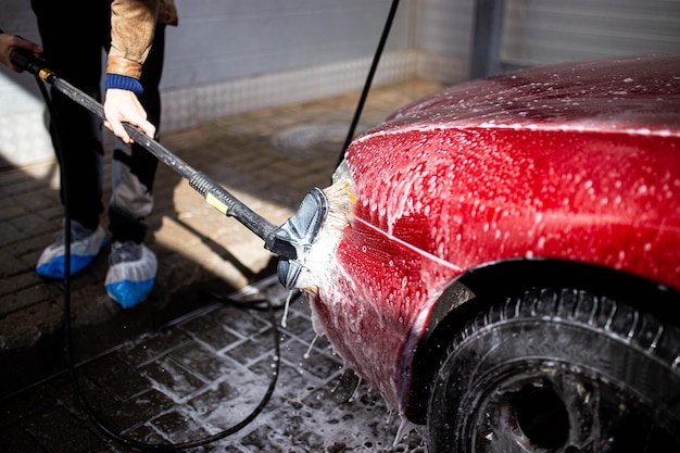 washing red car with brush and pressure washer