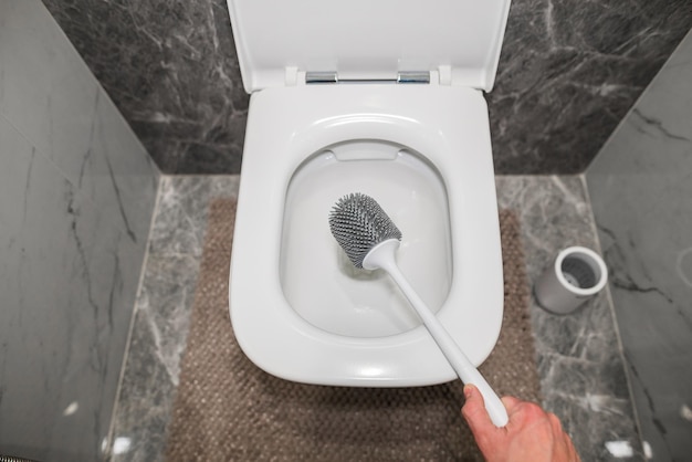 Washing the toilet with a gray silicone sponge