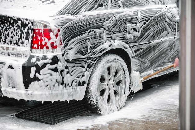 Washing wheels black car with household brush with a long handle