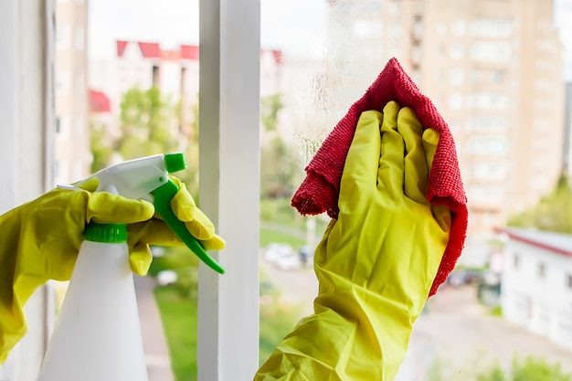 Washing windows. Woman in yellow rubber gloves wipes the glass.