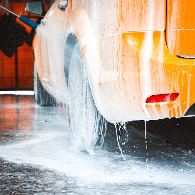 Washing a yellow car at a contactless selfservice car wash Washing a sedan car with foam and highpressure water