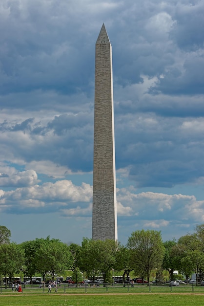 Foto washington, usa - 3 maggio 2015: il monumento di george washington è stato raffigurato nel parco vicino ad esso durante una giornata tempestosa e nuvolosa. la gente stava facendo una passeggiata anche durante una giornata del genere.