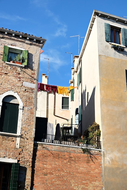 Waslijnen in een steegje in Venetië, Italië. Wasgoed hangt aan een waslijn tussen stadsgebouwen. Waslijnen tussen oude bakstenen huizen.
