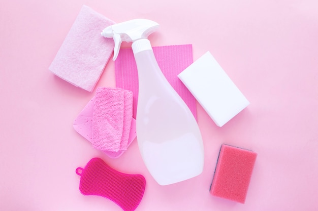 Wasmiddel en schoonmaakmiddel, sponzen, servetten en rubberen handschoenen, roze achtergrond.