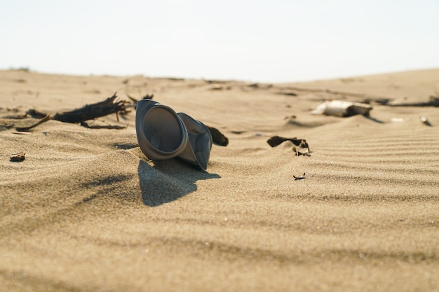 Waste can and other rubbish and trash abandoned in a pristine\
sand desert environment