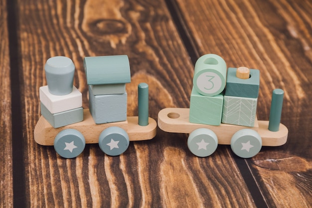 Фото Безотходное производство. фотография деревянного паровоза с голубой крышей на деревянном фоне. концепция развивающих детских игрушек из эко материалов.
