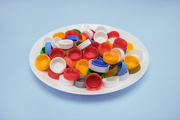 Waste plastic lids in white plate on blue background the concept of recycling zero waste production