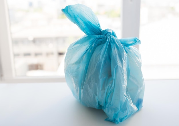 waste recycling, reuse, garbage disposal, environment and ecology concept - close up of rubbish bag with trash or garbage at home