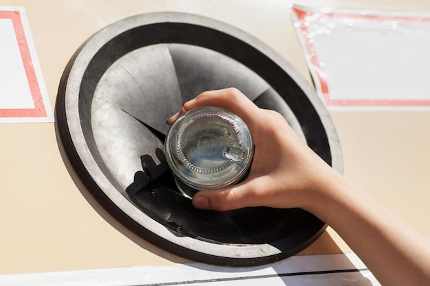 Waste Sorting And Recycling Concept Throwing Glass bottle into recycle bin garbage container