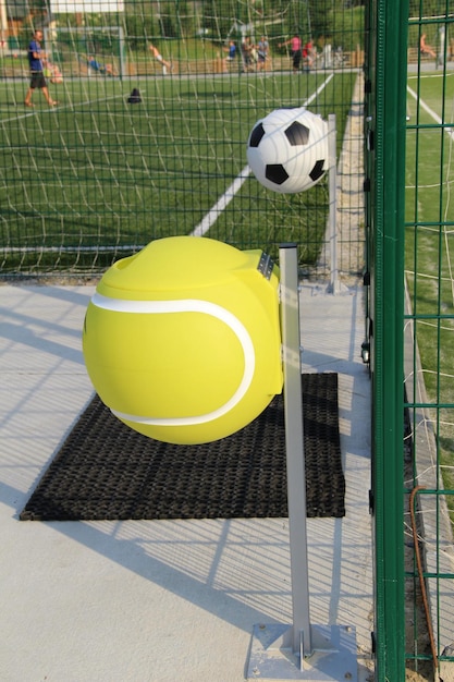 Wastebaskets in the shape of a sports balls near fenced sports court