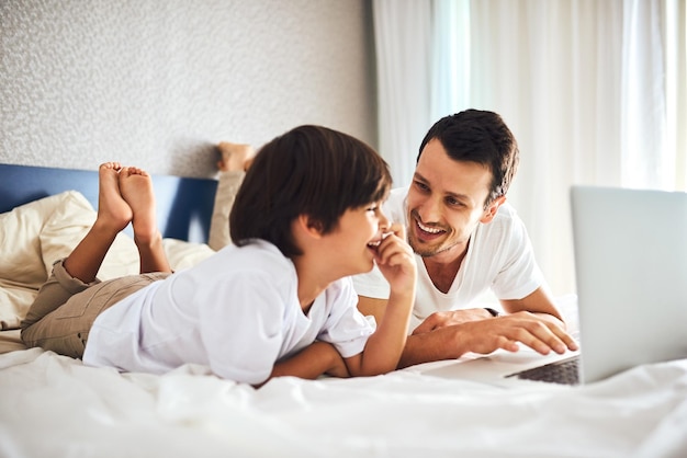 Wat dacht je ervan om samen een paar van je favoriete tekenfilms te kijken. shot van een vader en zijn zoontje die thuis samen een laptop gebruiken