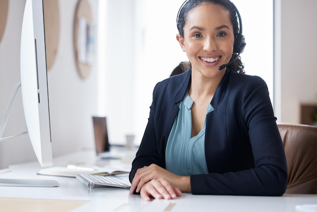 Wat kan ik vandaag voor u doen Bijgesneden portret van een aantrekkelijke jonge vrouwelijke callcenteragent die aan haar bureau op kantoor werkt