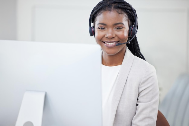 Wat kan ik vandaag voor u doen. Shot van een jonge Afrikaanse vrouw die op haar pc in een callcenter werkt.