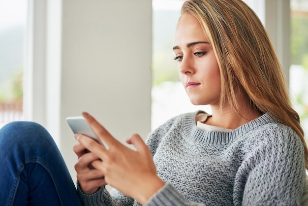 Wat sms'jes naar haar vrienden sturen Bijgesneden opname van een aantrekkelijke jonge vrouw die een sms stuurt terwijl ze thuis aan het chillen is