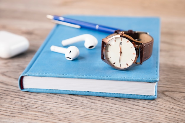 Watch and earphone with book on table