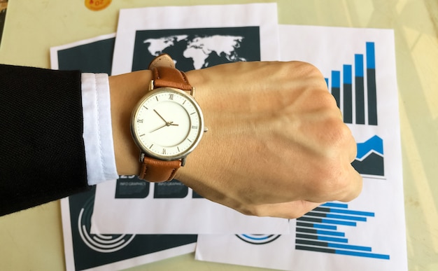 Photo watch on the left hand of business man with data report background