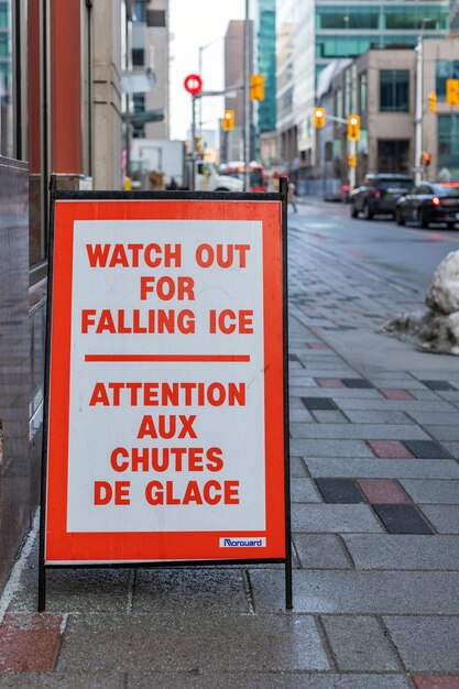 Watch out of falling snow and ice sign on the sidewalk warning of the danger