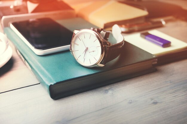 Photo watch and phone on book,cup of coffee on wooden  table