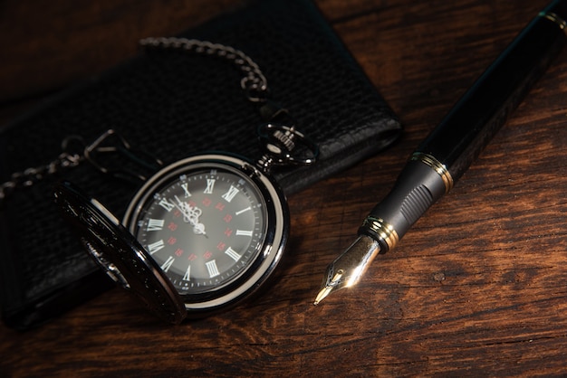 Guarda tasca vintage e penna stilografica in primo piano su una superficie di legno rustica.