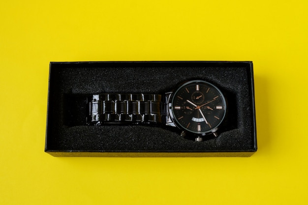 Watch, with black cardboard isolated on yellow background