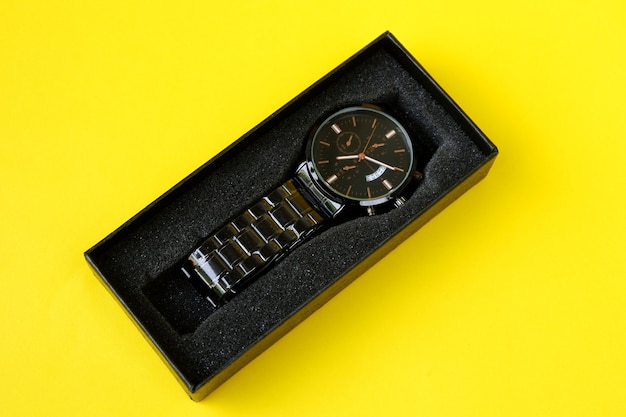 Foto orologio, con cartoncino nero isolato su sfondo giallo