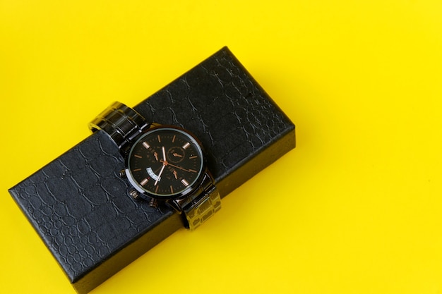 Watch, with black cardboard isolated on yellow background