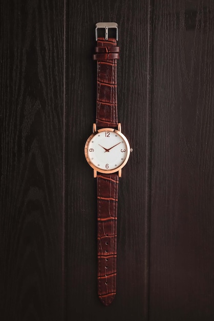 Watch with brown leather strap on the wooden table