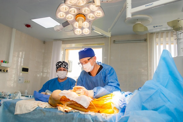 Watchful nurse performing an operation under the bright electric lamp in a modern operation center