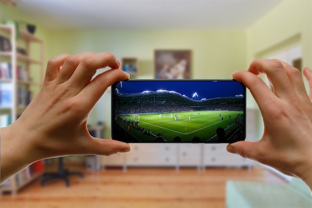 Foto guardare la partita di calcio a casa tramite smartphone. trasmissione di calcio dallo stadio.