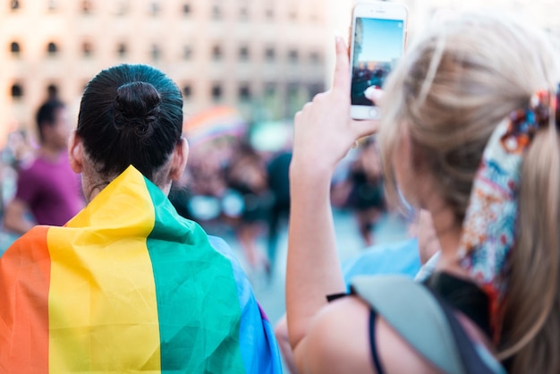 Foto guardando la parata dell'orgoglio gay giovane ragazza che registra l'evento con il suo telefono cellulare