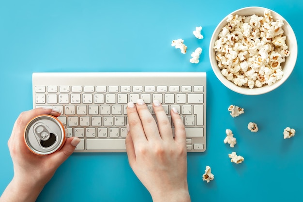 Watching movies with popcorn on a blue background flat lay