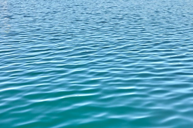 Водный фон с рябью и копирайтом Крупный план свежей спокойной голубой океанской воды во время отлива Увеличьте рябую поверхность воды с уникальными узорами движения Дзен спокойные маленькие медитативные волны