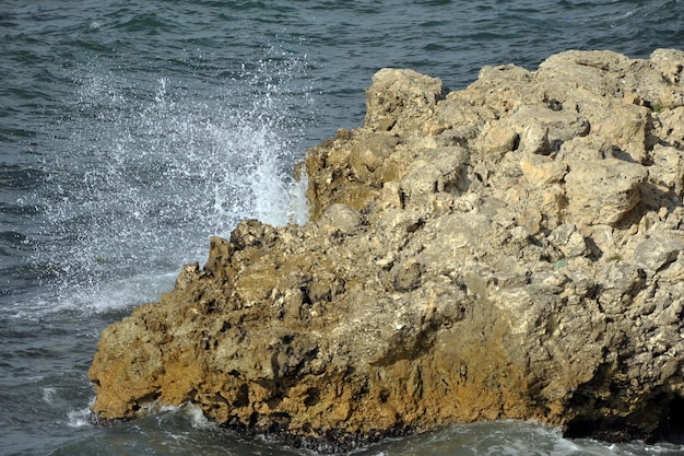 Вода бьется о камень в пенящихся волнах моря