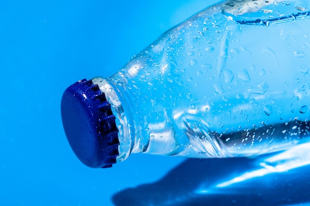 Бутылка воды крупным планом на синем