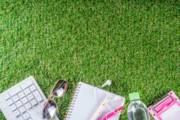 Water bottle, keyboard, notebook on green grass