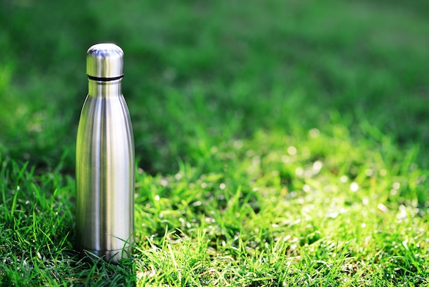 Water bottle reusable steel thermo water bottle on green grass