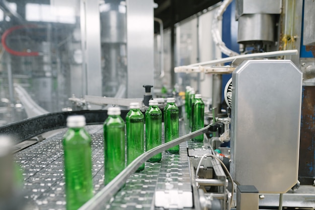 Photo water bottling line for processing and bottling pure mineral water into small green glass bottles. selective focus.