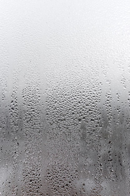 Water condensation on window glass background Outside  bad weather rain humidity and foggy blank Vertical natural background