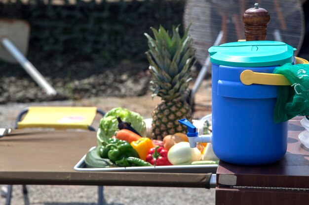 Foto contenitore d'acqua con varie frutta e verdura sul tavolo al campo
