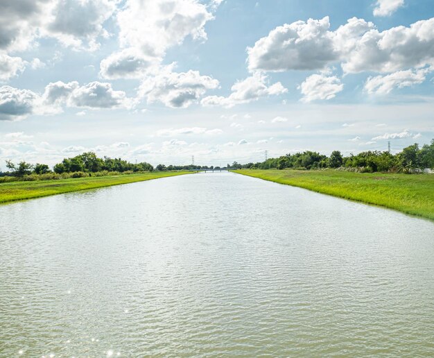 Водопроводные и распределительные каналы Ирригационный канал с тропой, проходящей вдоль него среди зеленого и голубого неба Красивый пейзаж в Банг-Лен Накхон-Патом Таиланд