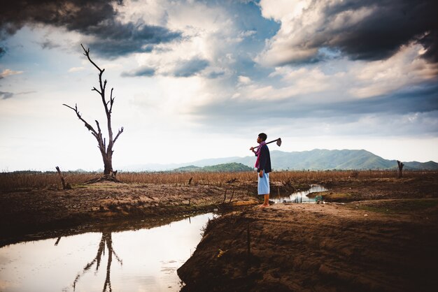 Il concetto di crisi idrica, l'agricoltore senza speranza e solo si siede sulla terra incrinata vicino all'acqua di secchezza.