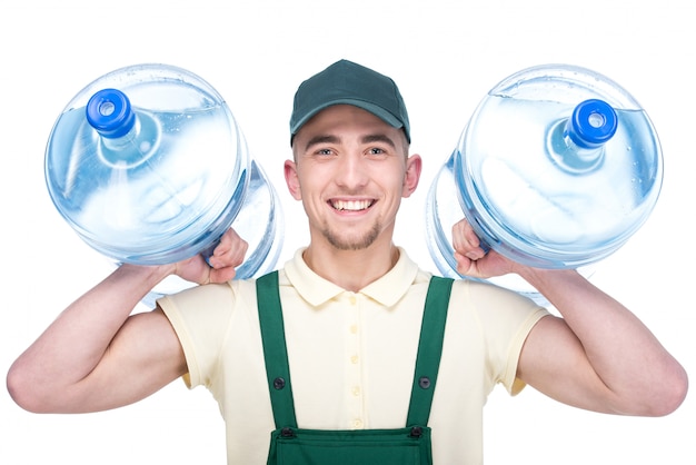 Water delivery courier is holding a two bottles.