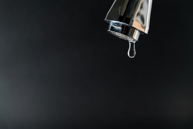 Water drop on faucet with  black backgrounds