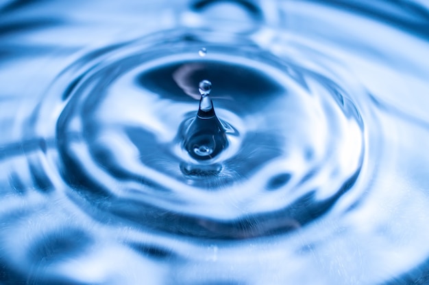 Water drop splash in a glass blue colored