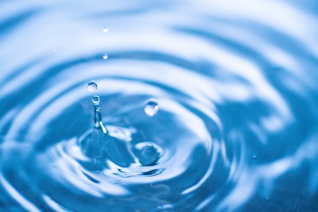 Water drop splash in a glass blue colored